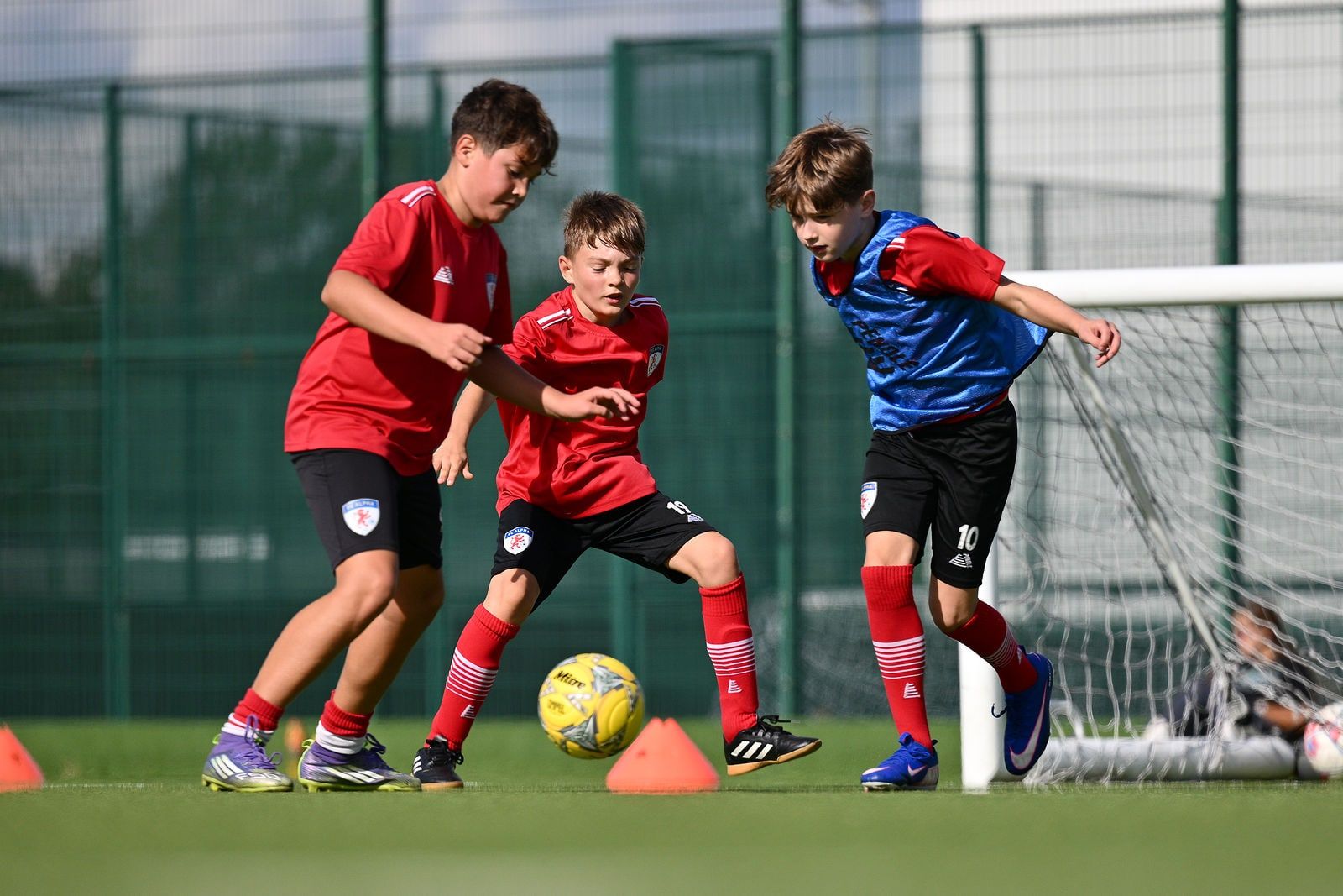 Three players chasing the ball near the goal