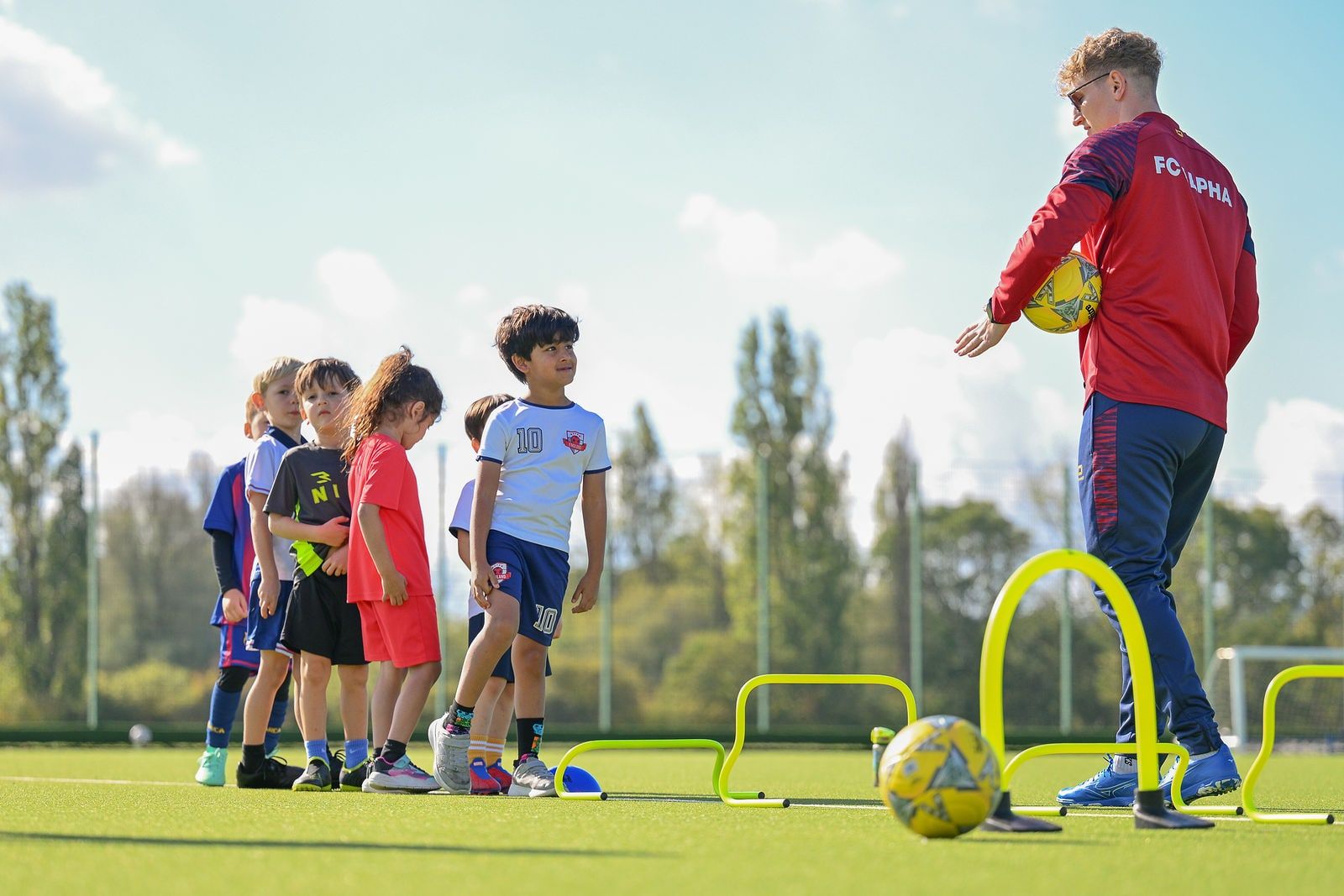 Young players lining up for a hurdles and ball drill