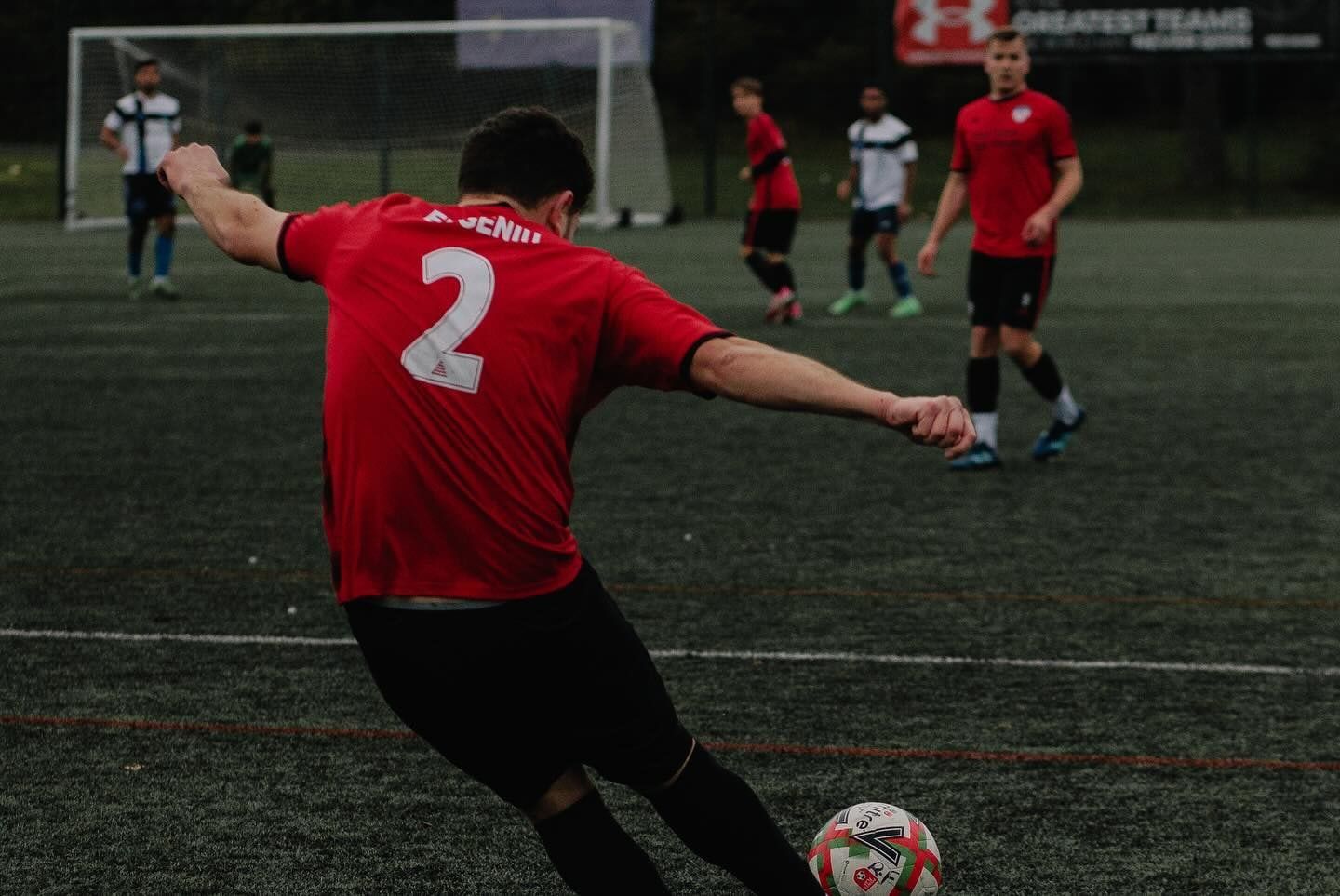 An FC Alpha player striking the ball during a match