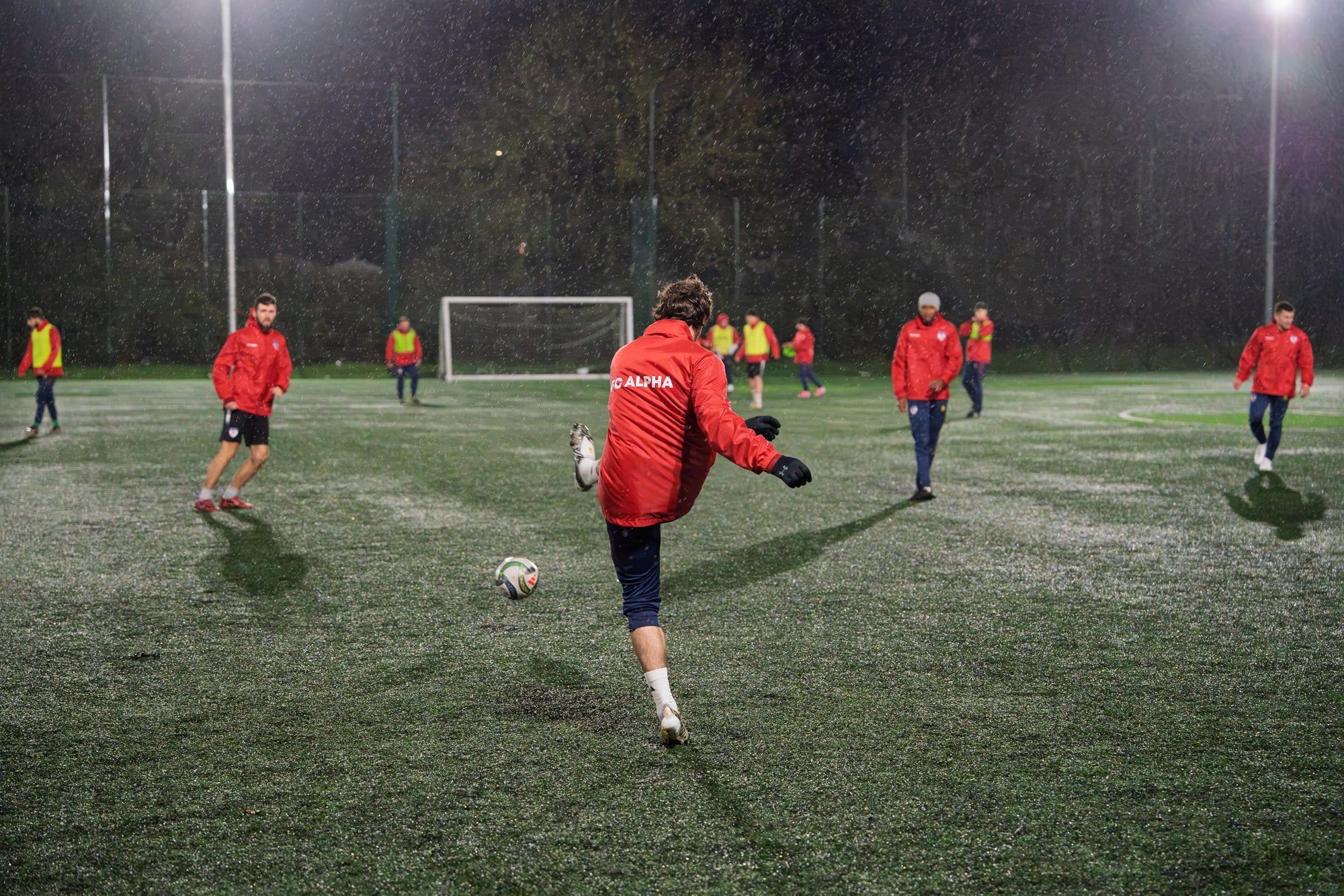A senior player striking the ball during a training game at night